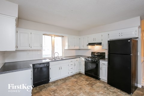 A kitchen with black appliances and white cabinets.