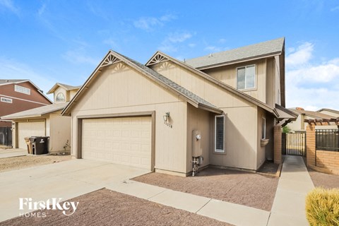 A beige house with a garage door and a brown driveway.