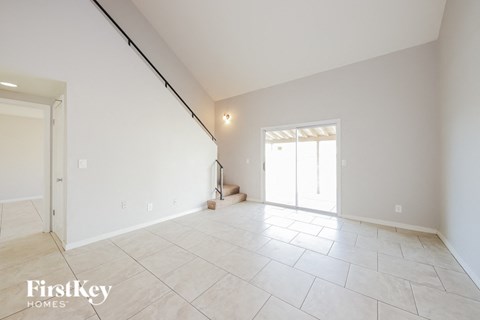 A spacious room with a tile floor and a window with blinds.