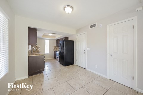 A kitchen area with a black fridge and a white door.