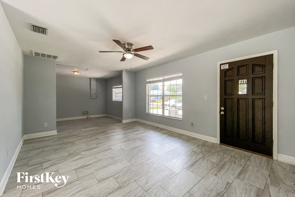 A spacious room with a ceiling fan and a door.
