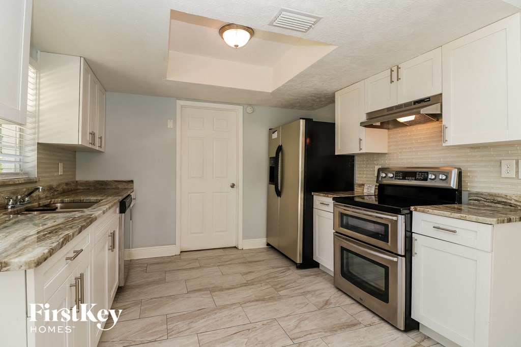 A kitchen with a black refrigerator and white cabinets.