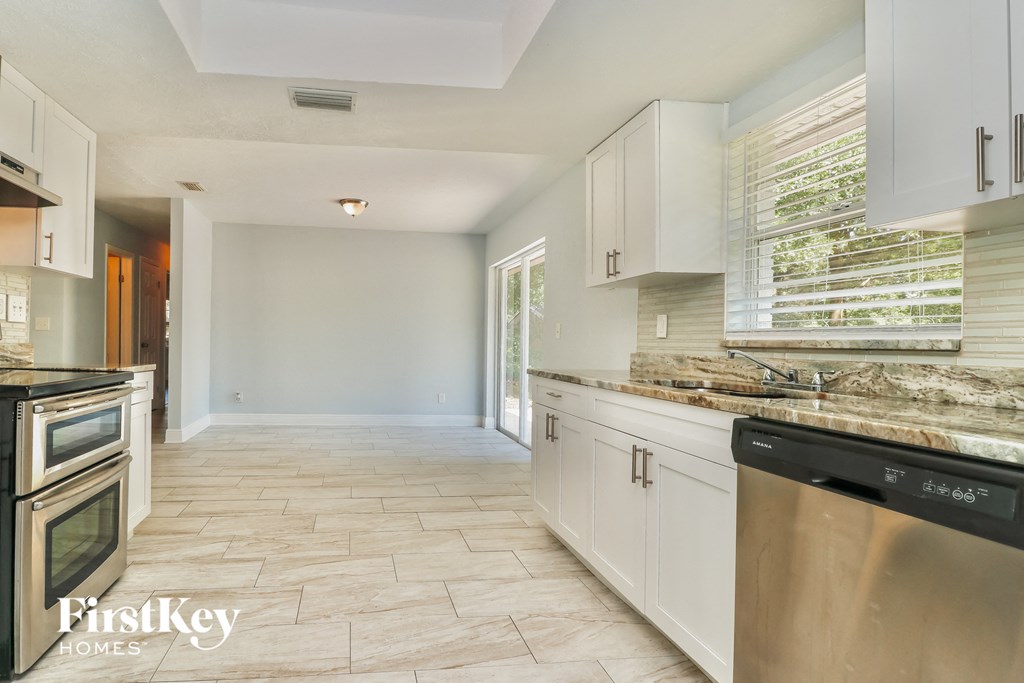 A kitchen with a stainless steel dishwasher and white cabinets.