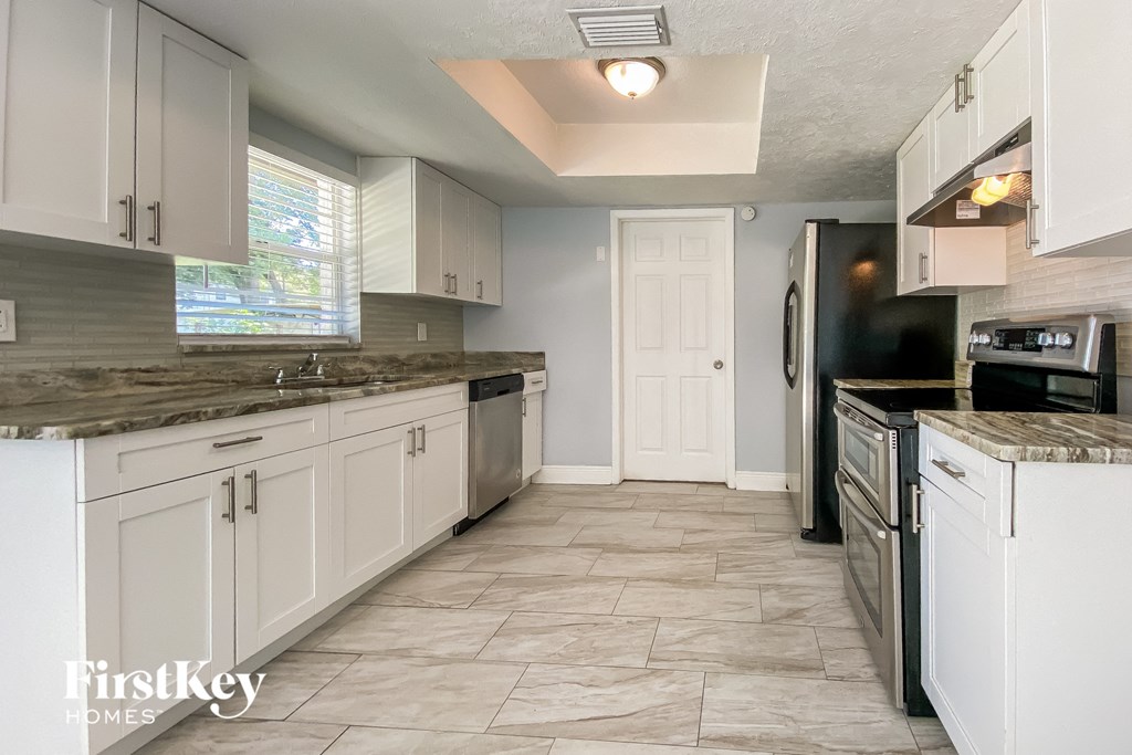 A kitchen with white cabinets and a tile floor.
