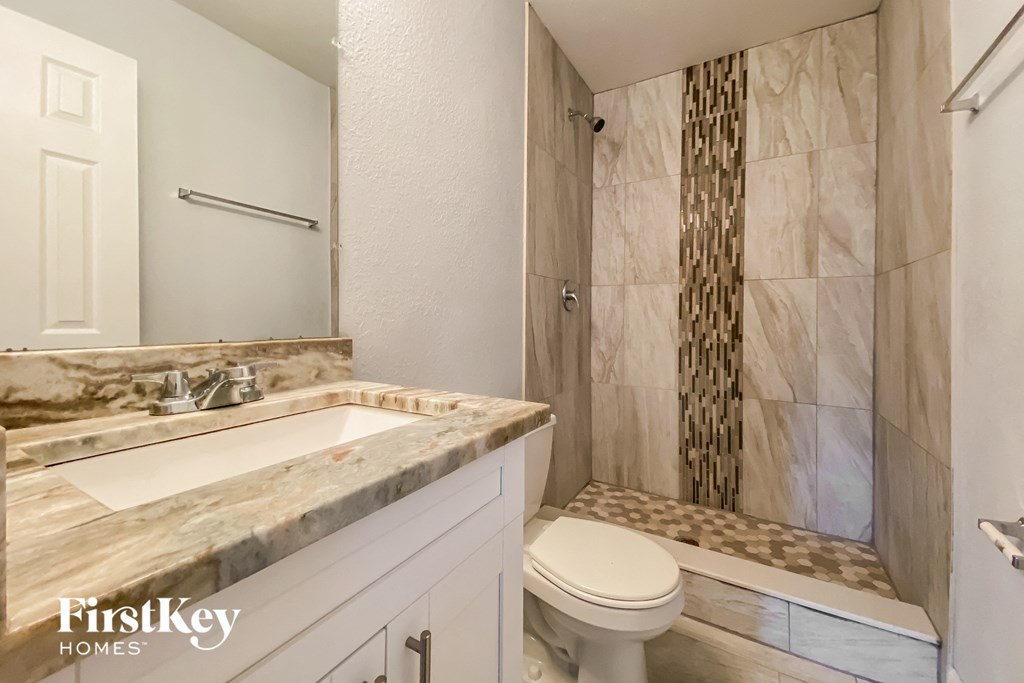 A bathroom with a marble countertop and a walk-in shower.