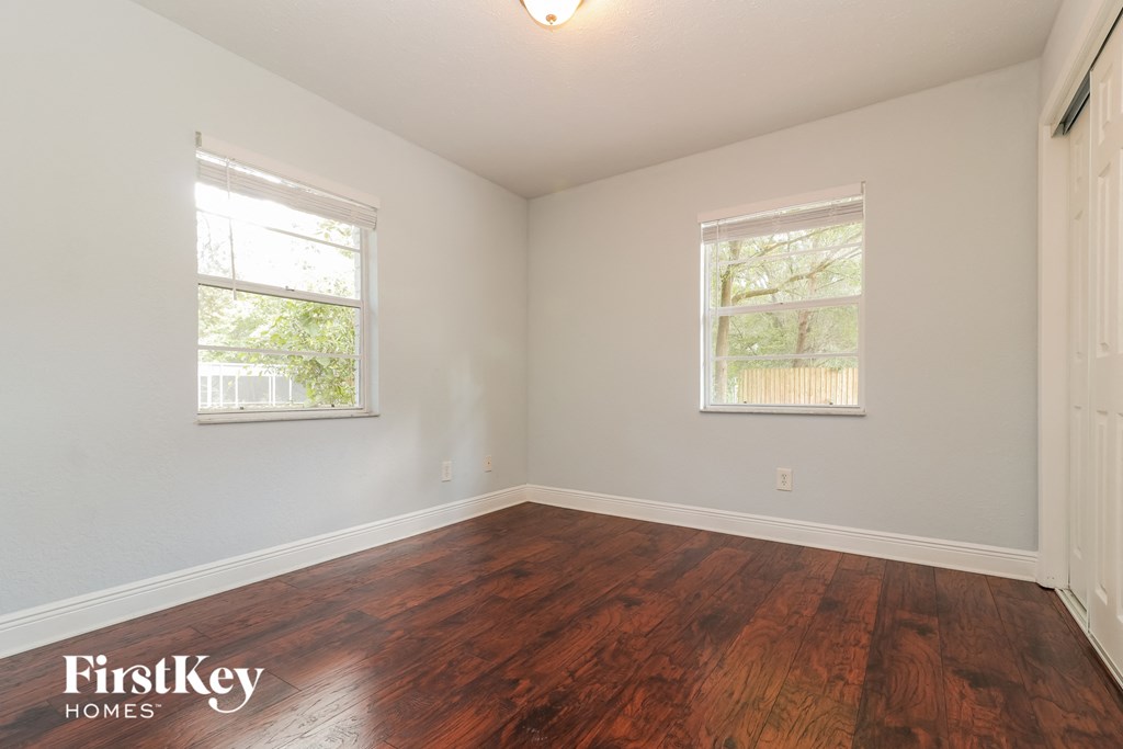A room with wooden floors and two windows.