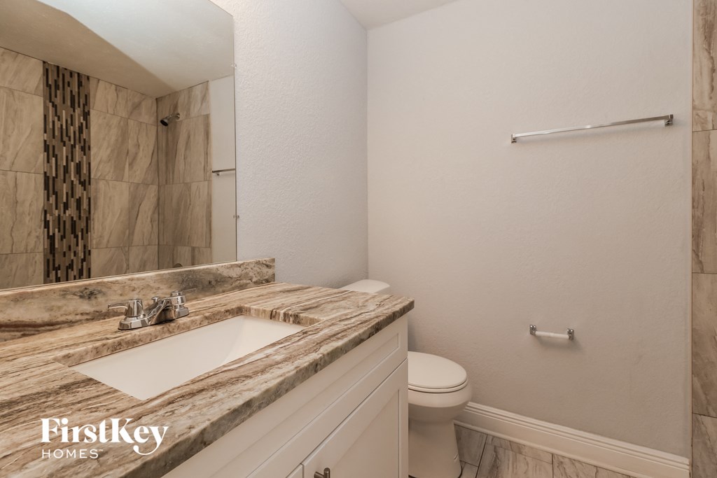 A bathroom with a marble countertop and a toilet.