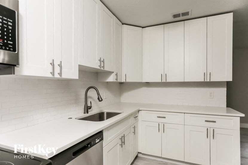 A kitchen with white cabinets and a stainless steel dishwasher.
