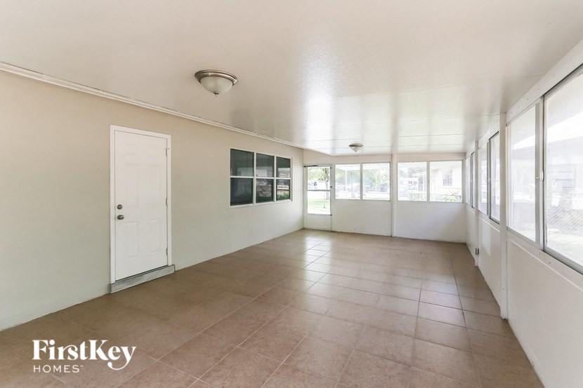 A room with a white door and a window with a view of trees.