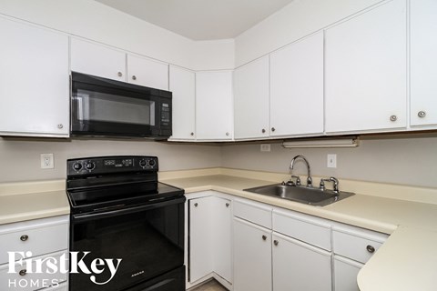 a kitchen with white cabinets and black appliances and a sink