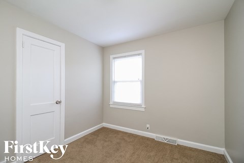a bedroom with a white door and a window and a carpet