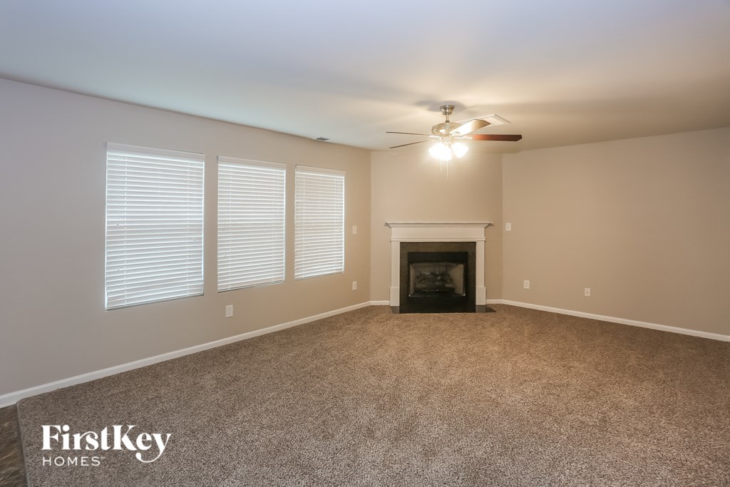 A spacious room with a fireplace and a ceiling fan.