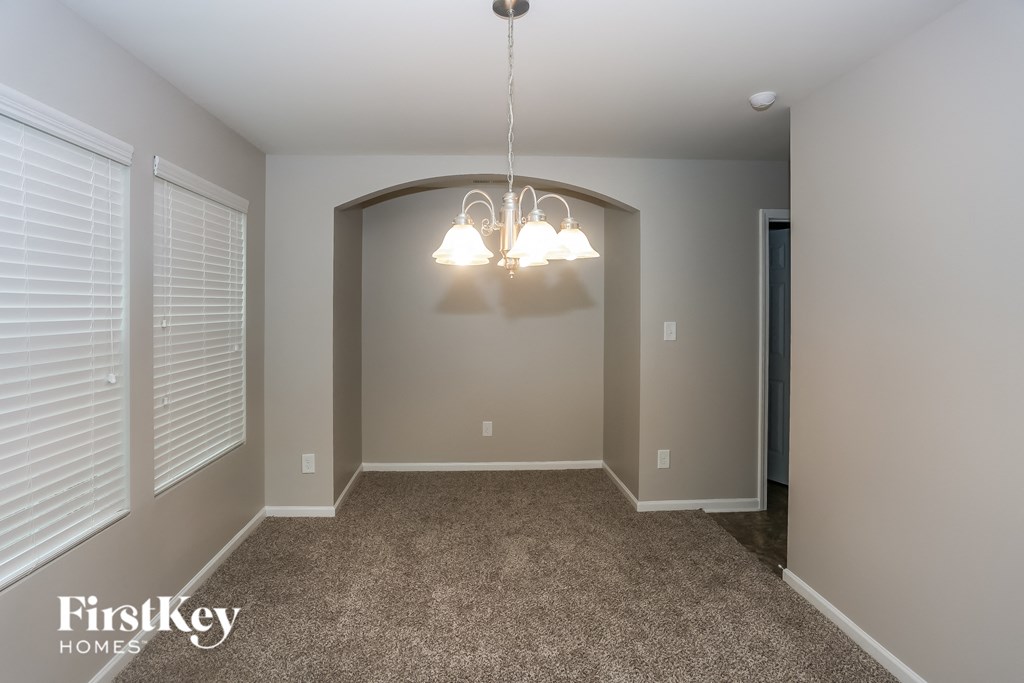 A well-lit room with a carpeted floor and a chandelier hanging from the ceiling.