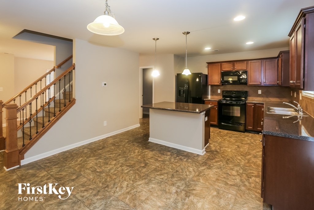 A kitchen with a refrigerator, microwave, and oven is shown in a home interior.
