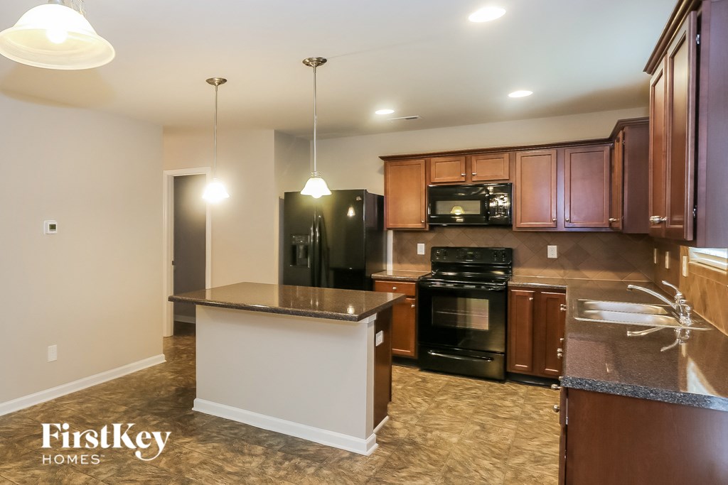 A kitchen with a black oven and brown cabinets.