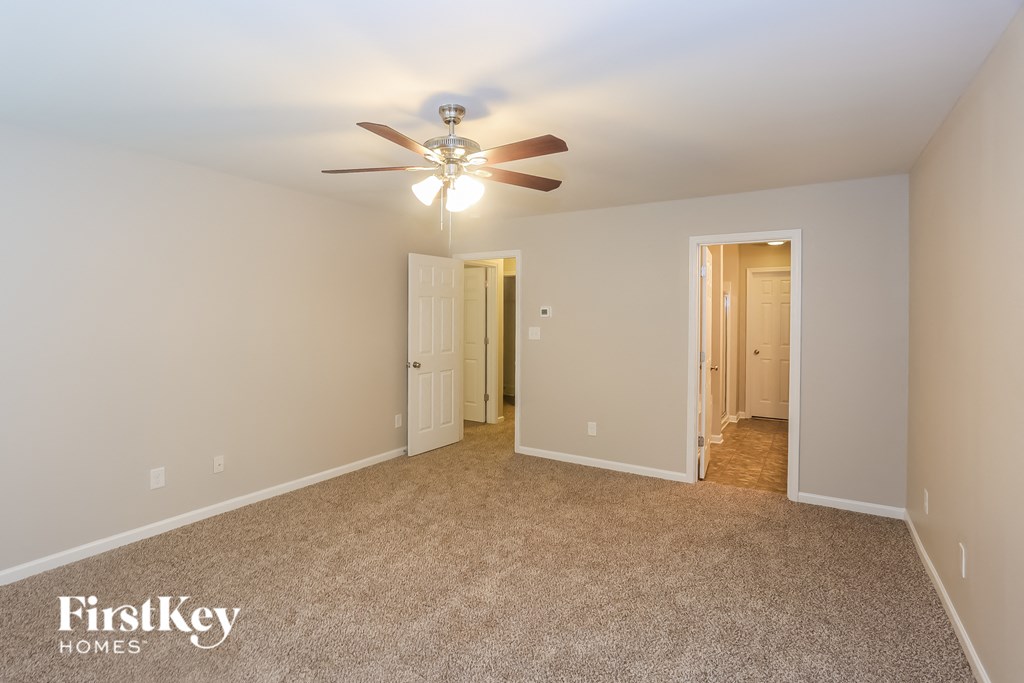 A spacious room with a ceiling fan and two doors.