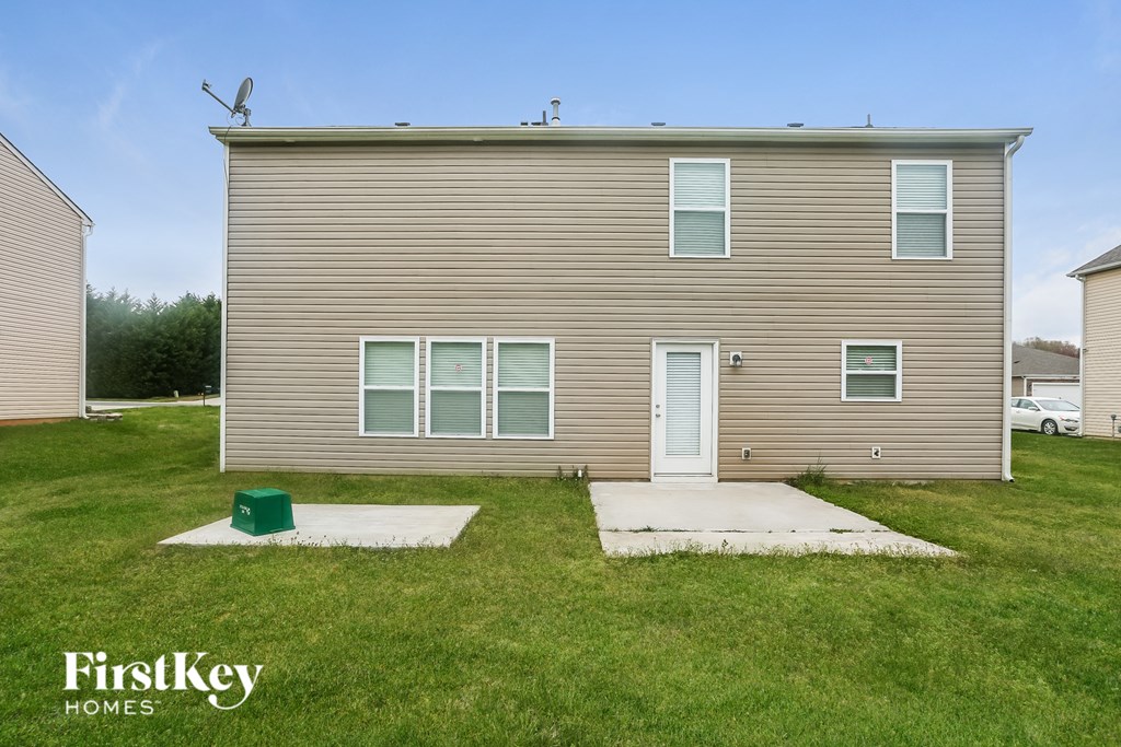 A two-story house with a green trash can in front of it.