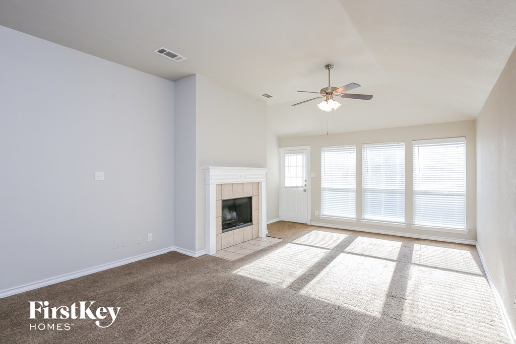 an empty living room with a ceiling fan and a fireplace
