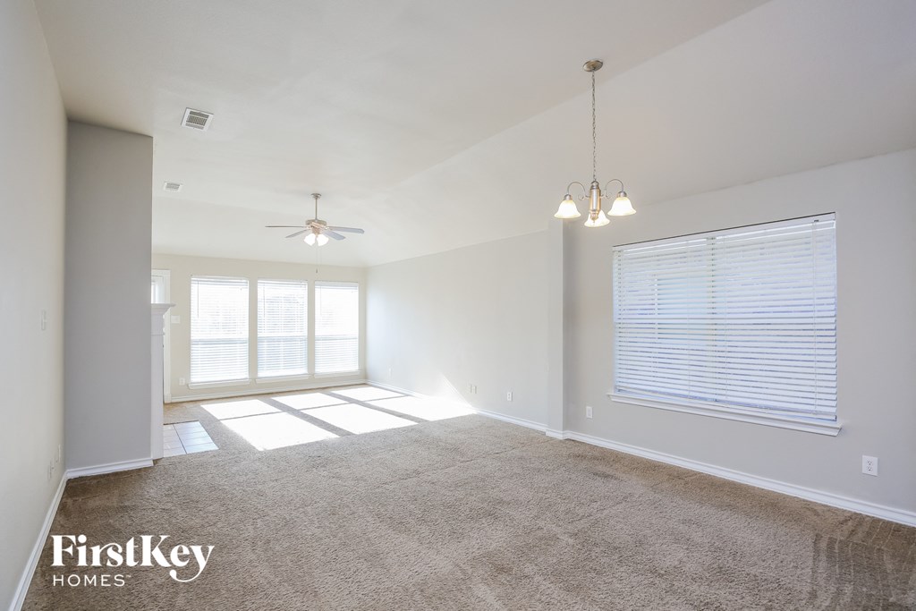 an empty living room with a window and a ceiling fan
