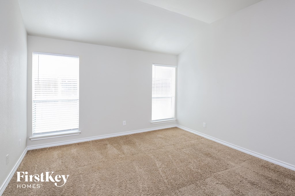a living room with a carpet and two windows