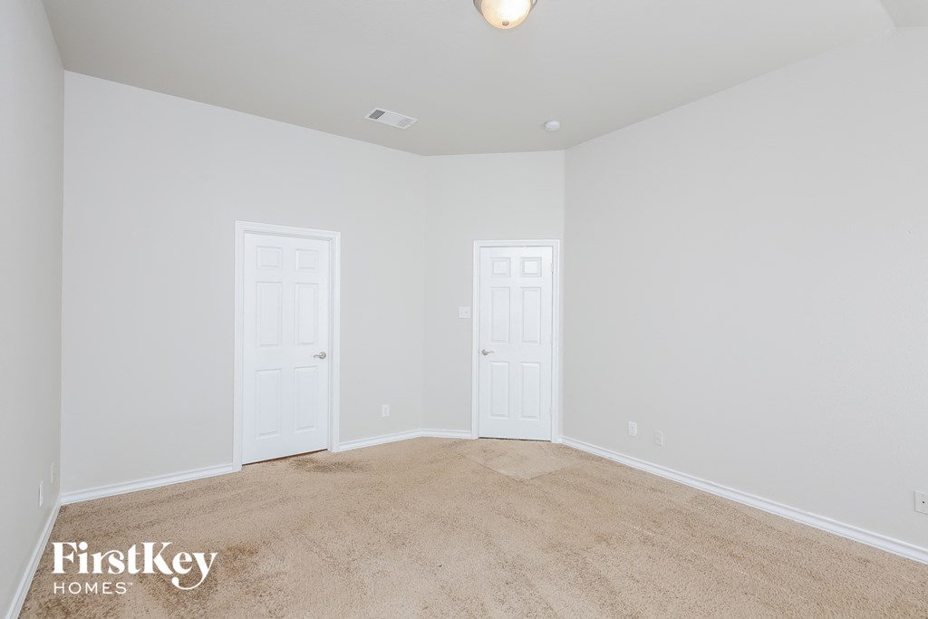 a bedroom with white walls and carpet and two doors