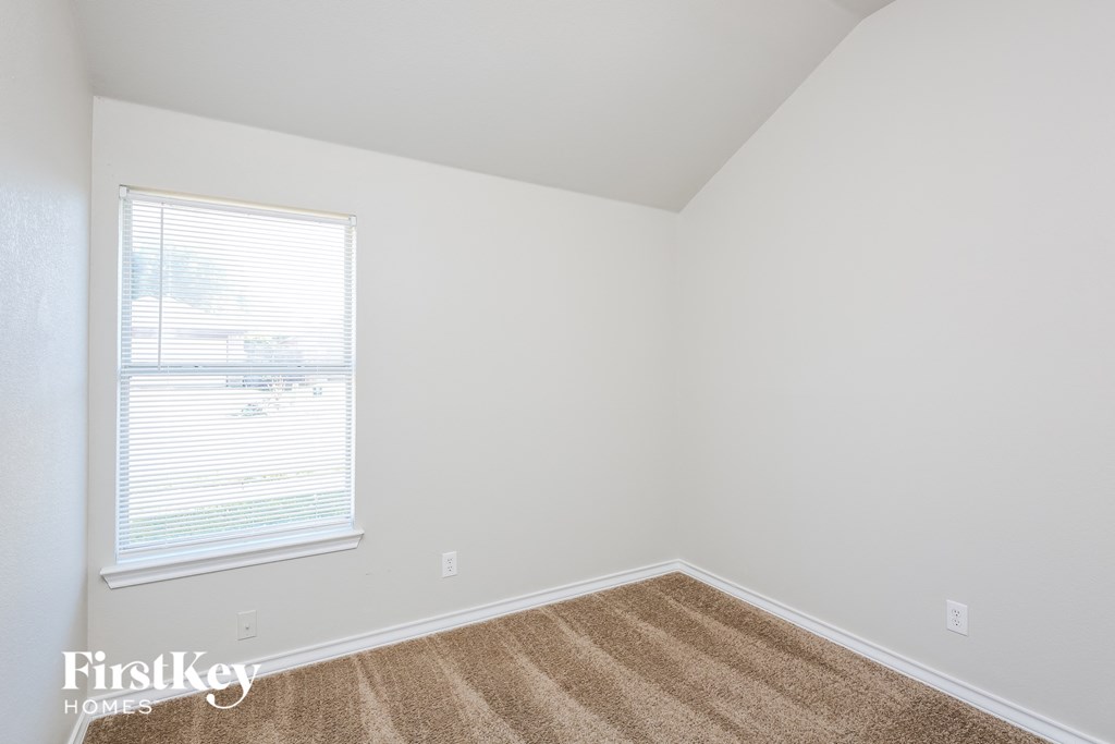 a bedroom with white walls and carpet and a window