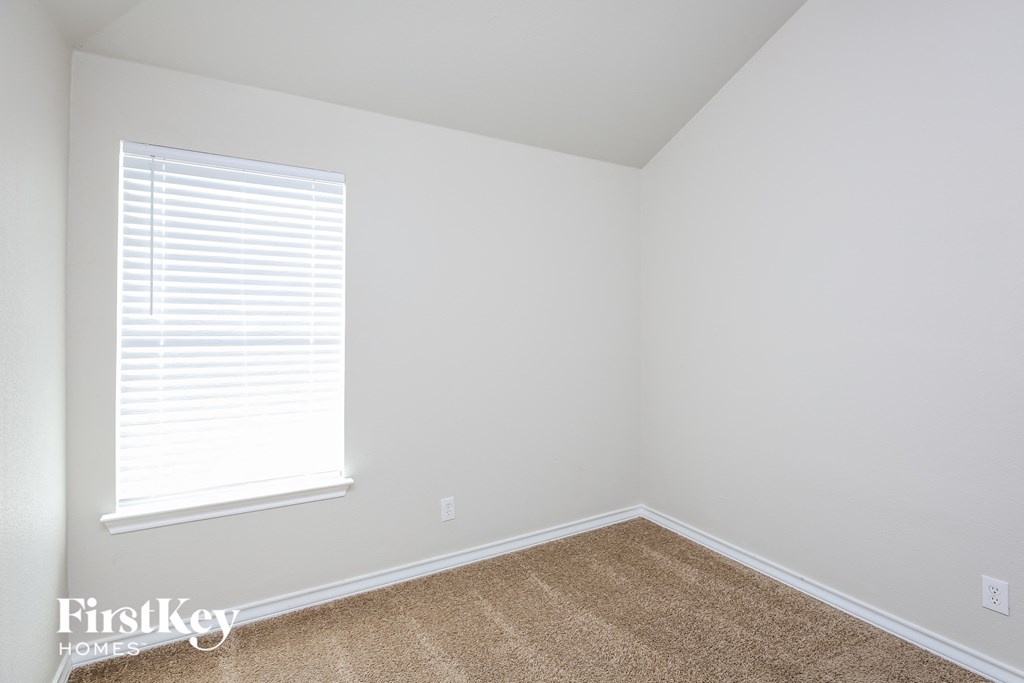 a bedroom with white walls and a window and a carpet