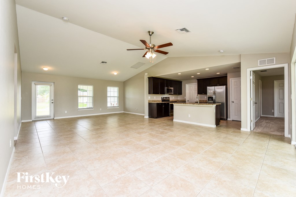 an empty kitchen and living room with a ceiling fan