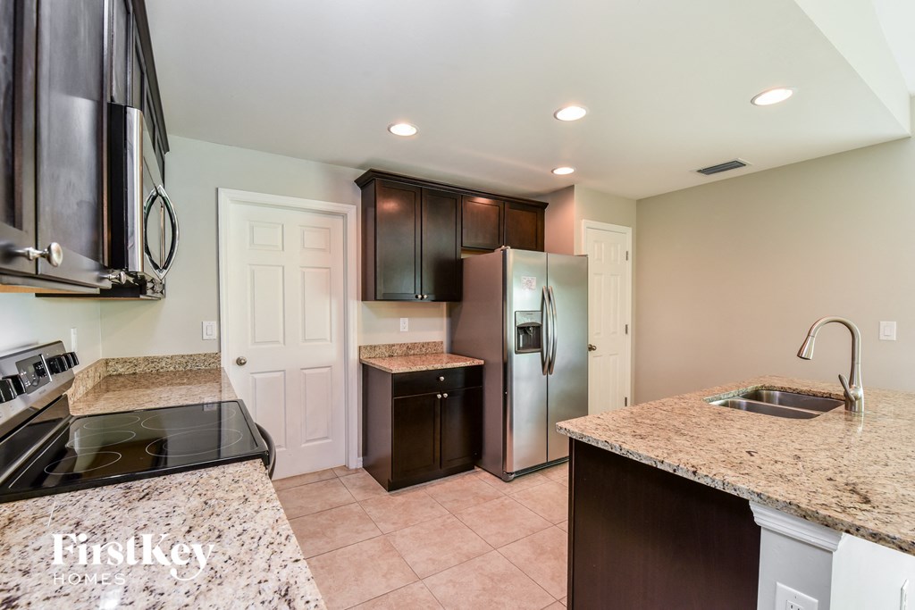 a kitchen with granite counter tops and a stainless steel refrigerator