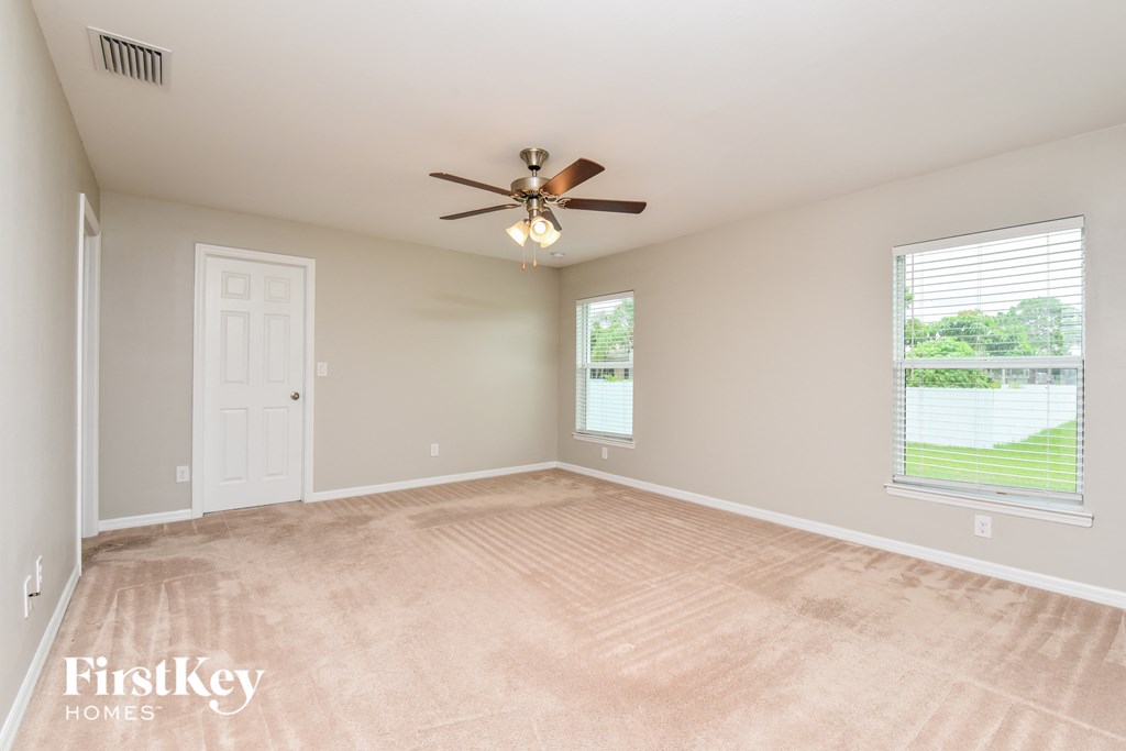 an empty living room with a ceiling fan and a window