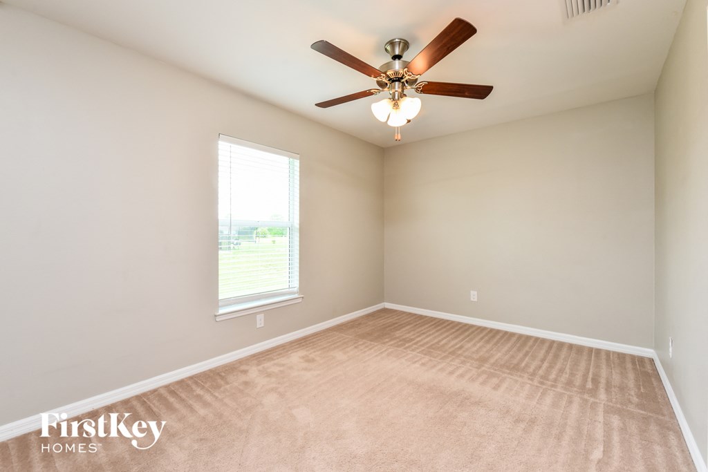 an empty living room with a ceiling fan and a window