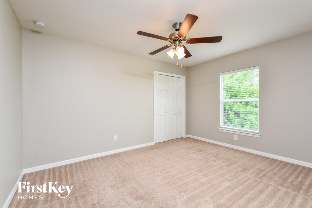 the spacious living room with ceiling fan and carpeting