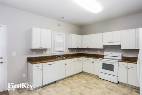 A kitchen with white cabinets and a brown countertop.