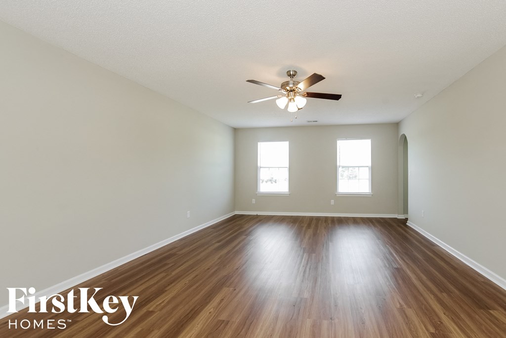 a spacious living room with hardwood floors and a ceiling fan