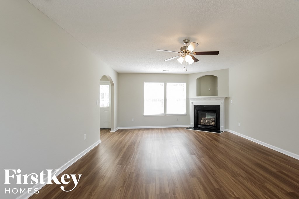 an empty living room with a ceiling fan and a fireplace