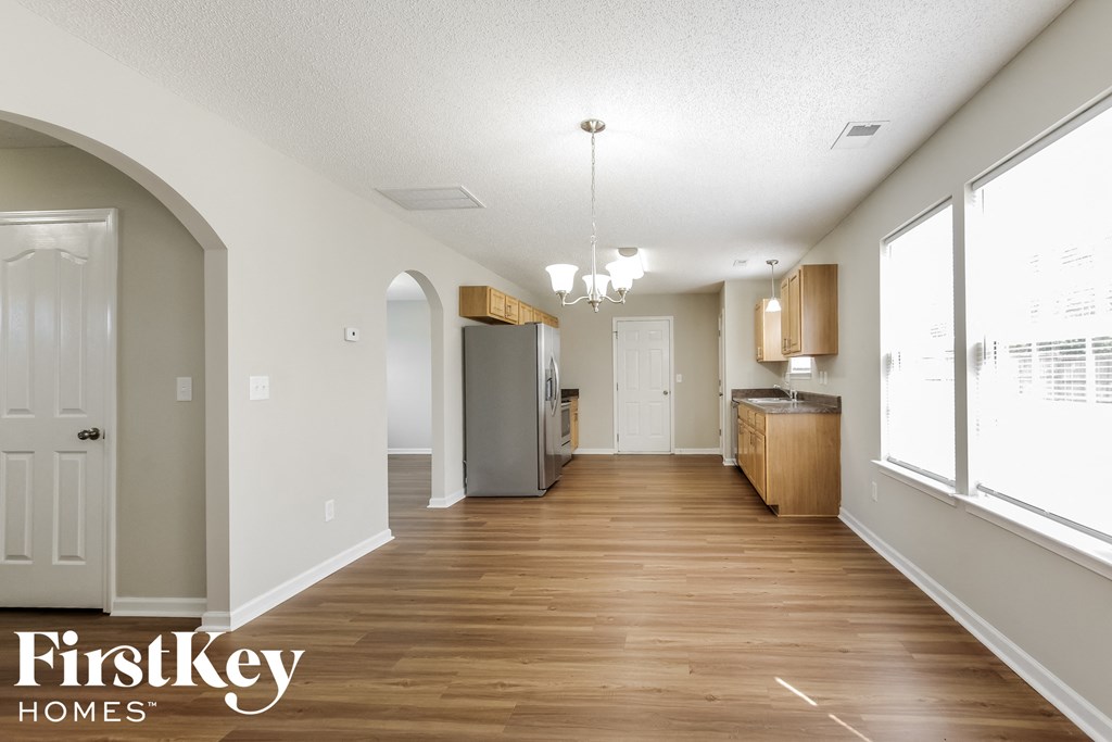 an empty kitchen and dining room with wood flooring and large windows