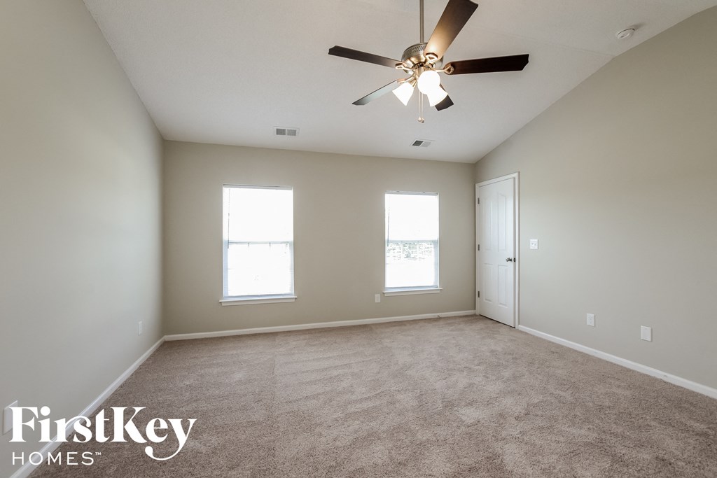an empty living room with a ceiling fan and two windows