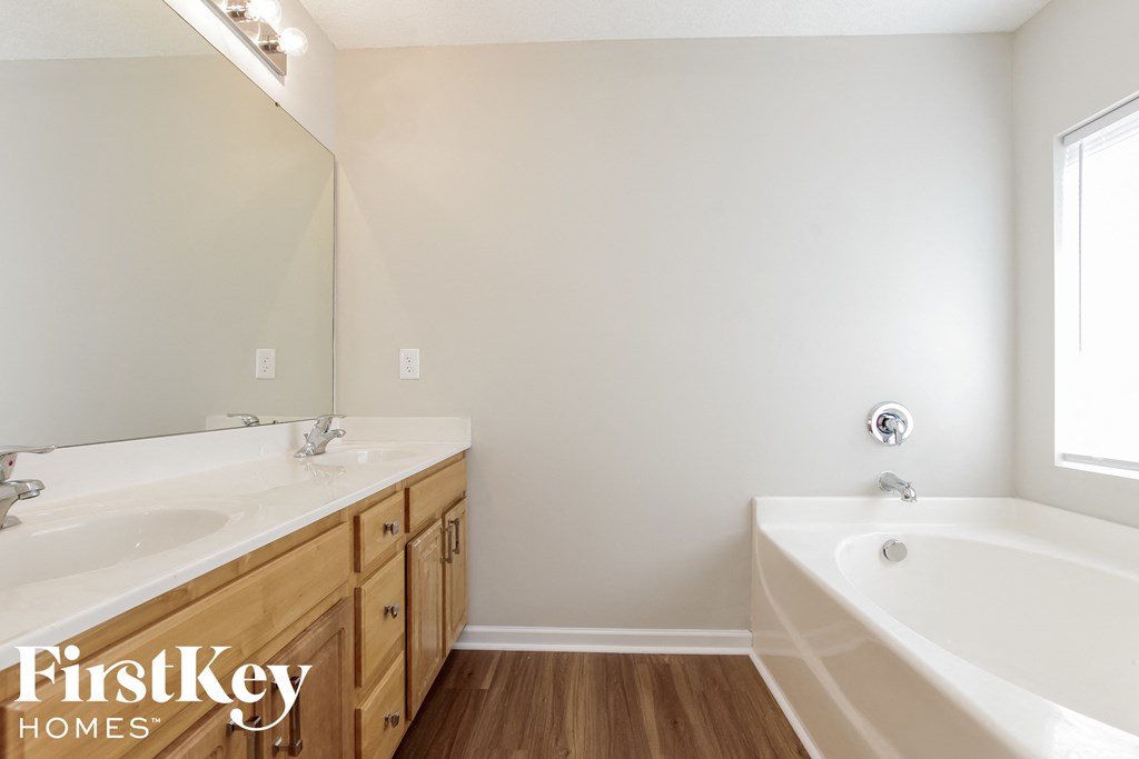 a bathroom with two sinks and a tub and a large mirror