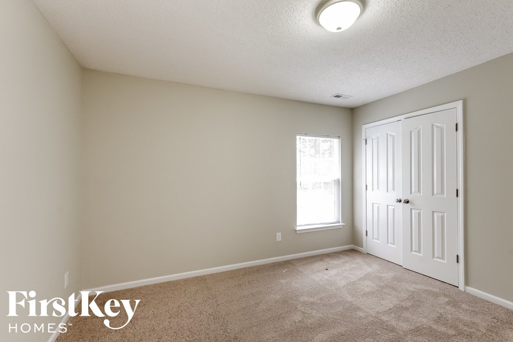 a bedroom with a white door and a carpeted floor