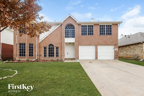 a brick house with a white garage door and a lawn