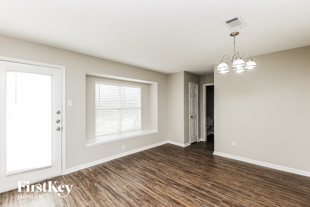 an empty living room with wood flooring and a window