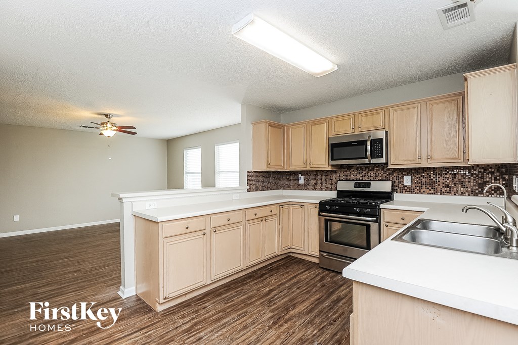 a kitchen with white counter tops and wooden flooring