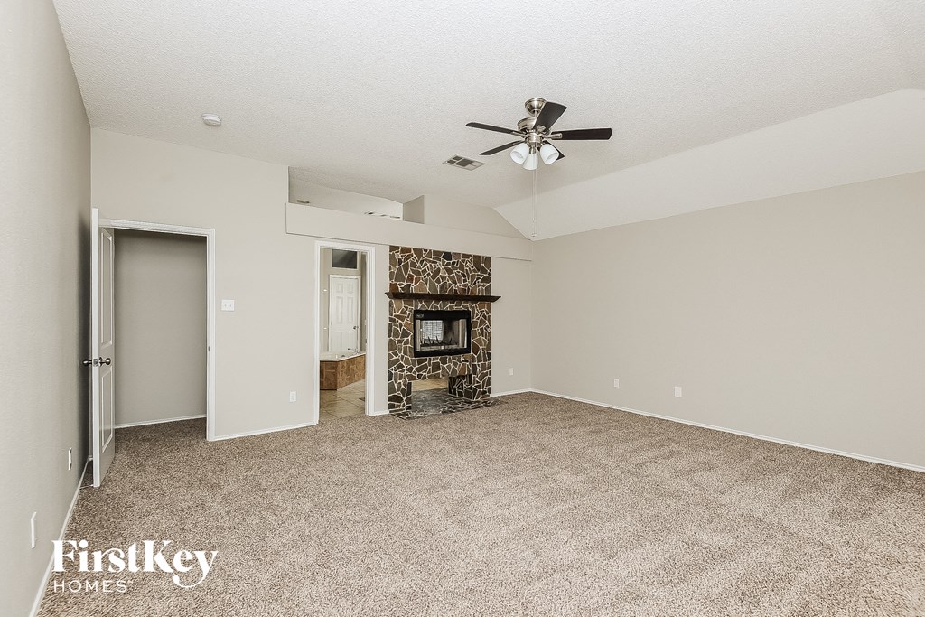 an empty living room with a fireplace and a ceiling fan