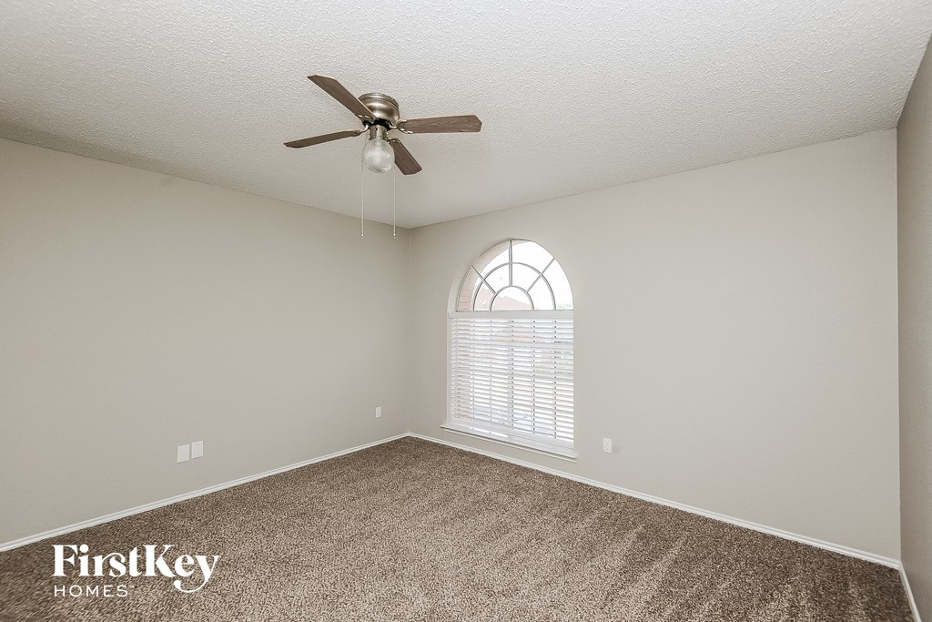 an empty room with a ceiling fan and a window
