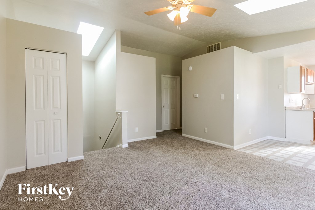 an empty living room with white walls and a ceiling fan