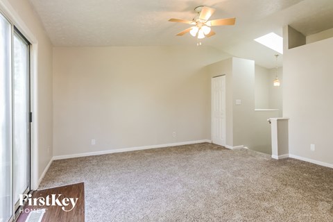 a spacious living room with carpet and a ceiling fan