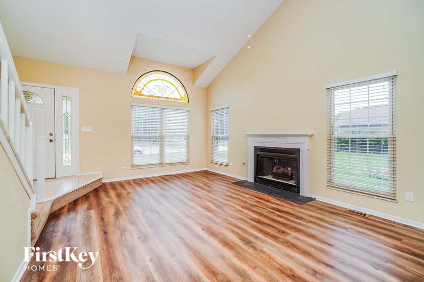 A spacious living room with a fireplace and a staircase.