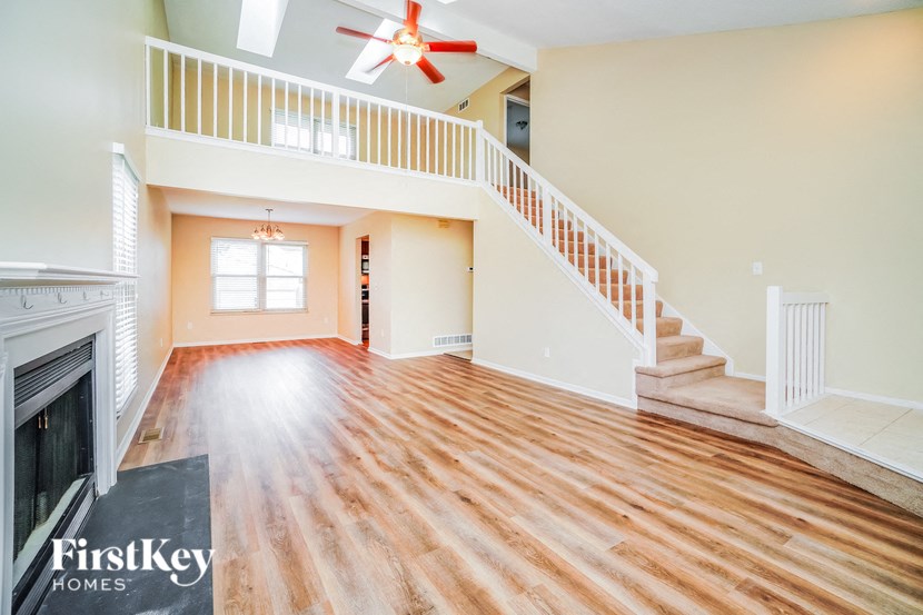A spacious living room with a staircase and a fireplace.