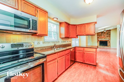 A kitchen with red cabinets and a black stove top oven.