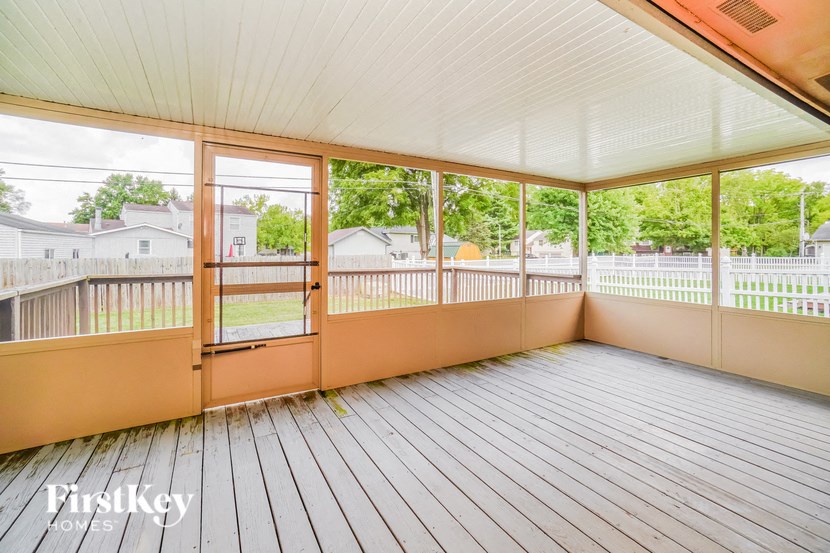 A wooden deck with a white ceiling and a view of a residential area.